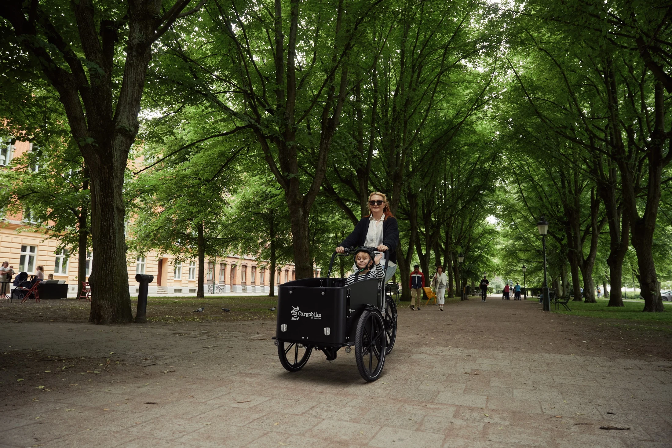 Mother and child on a cargo bike in a green city park in Sweden